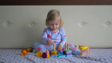 Küçük kız yatakta oyuncaklarla oynuyor. Genç kız rahat bir yatakta oyuncaklara daldı. Yatakta dinlenirken kendini oyun oynamaya kaptırmış bir kız. Küçük okuyucu yatağında oyuncakların tadını çıkarıyor.. 