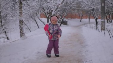 Genç kız karda oyuncaklarla neşeyle oynuyor. Çocuk, karlı bir günde neşeyle kürek fırlatıyor. Kız kış sahnesinde mutlu bir şekilde kardan adam fırlatıyor. Çocuk karlı parkta gülüyor ve kartoplarıyla eğleniyor. Küçük kız karla oynayan oyuncaklardan hoşlanıyor.