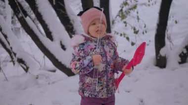 Genç kız karda oyuncaklarla neşeyle oynuyor. Çocuk, karlı bir günde neşeyle kürek fırlatıyor. Kız kış sahnesinde mutlu bir şekilde kardan adam fırlatıyor. Çocuk karlı parkta gülüyor ve kartoplarıyla eğleniyor. Küçük kız karla oynayan oyuncaklardan hoşlanıyor.
