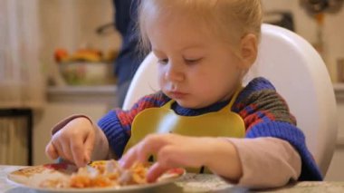 Mutlu kız yemeğin tadını çıkarıyor. Küçük çocuk mutlu bir şekilde öğle yemeği yiyor. Küçük kız yemeğinin tadını çıkarıyor. Elinde bir tabak yemekle gülümseyen kız. Neşeli çocuk lezzetli bir yemeğin içine sokuluyor..