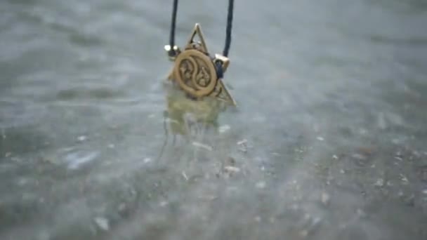 吉祥物的装饰沉入水中 这个女孩拿着一把金属护身符在波浪之上 — 图库视频影像