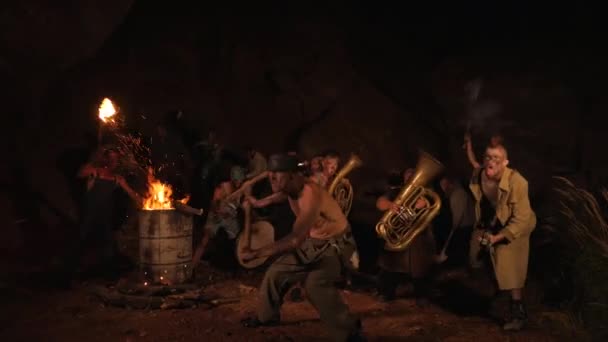 ドワーフや宝のハンターからの儀式ダンス 面白いミュージシャンが夜の洞窟で地下で遊んでいる 狂った人 トロール ゴブリンは楽器を演奏する 洞窟の設定内の明らかな火の近くに立っている個人のシルエット — ストック動画