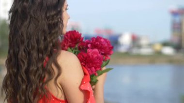 Turuncu elbiseli kız dışarıda kırmızı şakayık buketi tutuyor. Genç bir kız model plajda yatıyor. Güzel nehir kıyısı ve kum. Hayalindeki kız elinde kırmızı çiçekler tutuyor. Kadın kocasını düşünüyor.. 