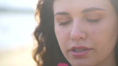 Turuncu elbiseli kız dışarıda kırmızı şakayık buketi tutuyor. Genç bir kız model plajda yatıyor. Güzel nehir kıyısı ve kum. Hayalindeki kız elinde kırmızı çiçekler tutuyor. Kadın kocasını düşünüyor.. 