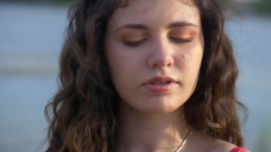 Turuncu elbiseli kız dışarıda kırmızı şakayık buketi tutuyor. Genç bir kız model plajda yatıyor. Güzel nehir kıyısı ve kum. Hayalindeki kız elinde kırmızı çiçekler tutuyor. Kadın kocasını düşünüyor.. 