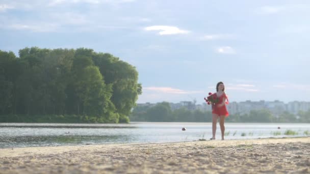 꽃다발 야외를 오렌지 드레스에 모델은 해변에 누워있다 아름다운 강둑과 꿈꾸는 — 비디오