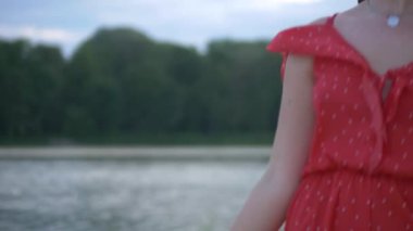 Genç bir kız model plajda dinlenir ve poz verir. Güzel kırmızı elbise. Seksi kız kendine sarılıyor, hayaller kuruyor. Kadın nehrin ve büyük evin arka planında duruyor. Model kameraya seksi bir bakışla bakıyor. Güzel nehir kıyısı ve... 