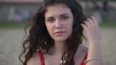 Genç bir kız model plajda dinlenir ve poz verir. Güzel kırmızı elbise. Seksi kız kendine sarılıyor, hayaller kuruyor. Kadın nehrin ve büyük evin arka planında duruyor. Model kameraya seksi bir bakışla bakıyor. Güzel nehir kıyısı ve... 