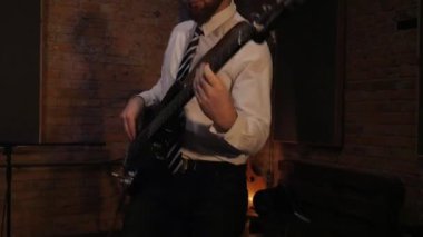 Bas gitar çalan adam. Komik iş adamları müzik enstrümanları çalar. Konser veren ofis çalışanları tarzında bir rock grubu. Stüdyoda akordeon, gitar ve davul çalan bir grup adam. Kravatlı ve ceketli adamlar, takım elbiseliler eğleniyor. 