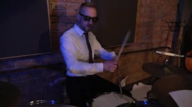 Davul çalan adam. Davulcu. Komik iş adamları müzik enstrümanları çalar. Konser veren ofis çalışanları tarzında bir rock grubu. Stüdyoda akordeon, gitar ve davul çalan bir grup adam. Kravatlı ve ceketli adamlar, takım elbiseliler eğleniyor.