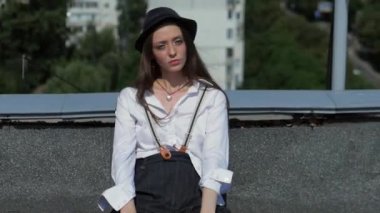 Beyaz gömlekli ve şapkalı kadın çatıda. Çatıda duran şık bir kadın. Güzel kız evin çatısında yürüyor. Kadın Roofer yüksek binaların çatısına tırmanır. Çatıda duran bir kadın. Çatıdaki kadın figürü. Binanın tepesindeki kişi