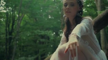 Çekici Dryad veya orman perisi. Ormanda şeffaf beyaz elbiseli hoş bir kadın. Mavka, Naiad, Nymph. Düğün kıyafetiyle bir ormanlık alanda gezinen bir gelinin büyüleyici bir sahnesi. Sihirli bir ormanda gezinen bir kadın