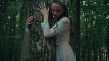 Çekici Dryad veya orman perisi. Ormanda şeffaf beyaz elbiseli hoş bir kadın. Mavka, Naiad, Nymph. Düğün kıyafetiyle bir ormanlık alanda gezinen bir gelinin büyüleyici bir sahnesi. Sihirli bir ormanda gezinen bir kadın