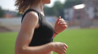 Stadyumda koşu yapan bayan sporcu. Güneşli bir günde stadyumda fiziksel egzersiz yapan ve spor yapan bayan sporcu. Spor salonunda kadın koşucu eğitimi. Dairesel stadyum pistinde koşan bir kadın. Stadyumda koşan bir kadın.