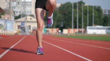 Stadyumda koşu yapan bayan sporcu. Güneşli bir günde stadyumda fiziksel egzersiz yapan ve spor yapan bayan sporcu. Spor salonunda kadın koşucu eğitimi. Dairesel stadyum pistinde koşan bir kadın. Stadyumda koşan bir kadın.