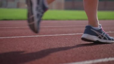 Stadyumda koşu yapan bayan sporcu. Güneşli bir günde stadyumda fiziksel egzersiz yapan ve spor yapan bayan sporcu. Spor salonunda kadın koşucu eğitimi. Dairesel stadyum pistinde koşan bir kadın. Stadyumda koşan bir kadın.