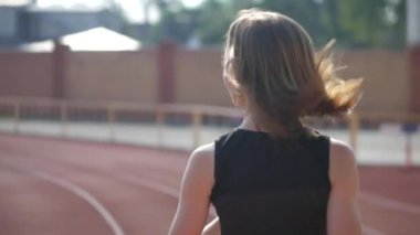 Stadyumda koşu yapan bayan sporcu. Güneşli bir günde stadyumda fiziksel egzersiz yapan ve spor yapan bayan sporcu. Spor salonunda kadın koşucu eğitimi. Dairesel stadyum pistinde koşan bir kadın. Stadyumda koşan bir kadın.