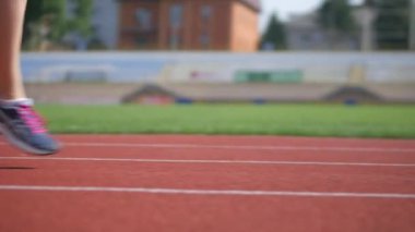Stadyumda koşu yapan bayan sporcu. Güneşli bir günde stadyumda fiziksel egzersiz yapan ve spor yapan bayan sporcu. Spor salonunda kadın koşucu eğitimi. Dairesel stadyum pistinde koşan bir kadın. Stadyumda koşan bir kadın.