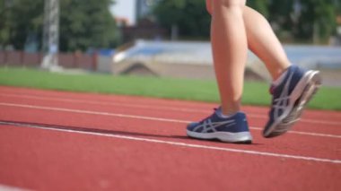 Stadyumda koşu yapan bayan sporcu. Güneşli bir günde stadyumda fiziksel egzersiz yapan ve spor yapan bayan sporcu. Spor salonunda kadın koşucu eğitimi. Dairesel stadyum pistinde koşan bir kadın. Stadyumda koşan bir kadın.