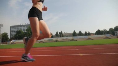 Stadyumda koşu yapan bayan sporcu. Güneşli bir günde stadyumda fiziksel egzersiz yapan ve spor yapan bayan sporcu. Spor salonunda kadın koşucu eğitimi. Dairesel stadyum pistinde koşan bir kadın. Stadyumda koşan bir kadın.