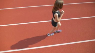 Stadyumda koşu yapan bayan sporcu. Güneşli bir günde stadyumda fiziksel egzersiz yapan ve spor yapan bayan sporcu. Spor salonunda kadın koşucu eğitimi. Dairesel stadyum pistinde koşan bir kadın. Stadyumda koşan bir kadın.