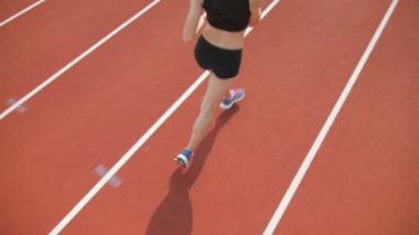Stadyumda koşu yapan bayan sporcu. Güneşli bir günde stadyumda fiziksel egzersiz yapan ve spor yapan bayan sporcu. Spor salonunda kadın koşucu eğitimi. Dairesel stadyum pistinde koşan bir kadın. Stadyumda koşan bir kadın.