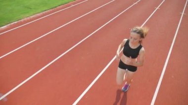 Stadyumda koşu yapan bayan sporcu. Güneşli bir günde stadyumda fiziksel egzersiz yapan ve spor yapan bayan sporcu. Spor salonunda kadın koşucu eğitimi. Dairesel stadyum pistinde koşan bir kadın. Stadyumda koşan bir kadın.