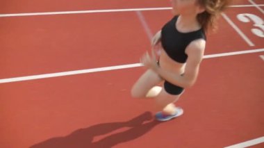 Stadyumda koşu yapan bayan sporcu. Güneşli bir günde stadyumda fiziksel egzersiz yapan ve spor yapan bayan sporcu. Spor salonunda kadın koşucu eğitimi. Dairesel stadyum pistinde koşan bir kadın. Stadyumda koşan bir kadın.
