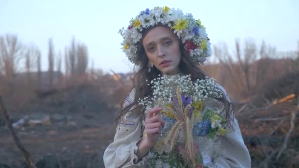 나무로 둘러싸인 드레스를 화환에있는 소녀는 숲에서 우크라이나어 드레스 우아한 사이에 — 비디오