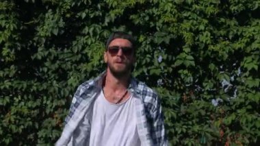 Şık bir adam şehrin sokaklarında dans figürleri yapıyor. Adam binaların arka planında hip-hop yapıyor. Profesyonel dansçı House Dansı ve Popping yapar. Hip hop dansçısı. Ekose gömlekli ve şortlu dansçı yüksekten atlıyor. Şehir dansçısı