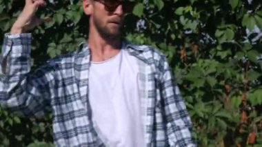 Şık bir adam şehrin sokaklarında dans figürleri yapıyor. Adam binaların arka planında hip-hop yapıyor. Profesyonel dansçı House Dansı ve Popping yapar. Hip hop dansçısı. Ekose gömlekli ve şortlu dansçı yüksekten atlıyor. Şehir dansçısı