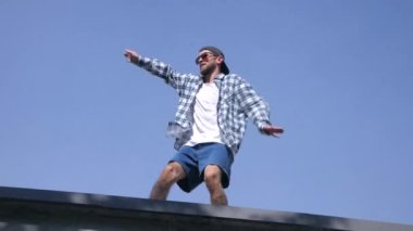 Şık bir adam şehrin sokaklarında dans figürleri yapıyor. Adam binaların arka planında hip-hop yapıyor. Profesyonel dansçı House Dansı ve Popping yapar. Hip hop dansçısı. Ekose gömlekli ve şortlu dansçı yüksekten atlıyor. Şehir dansçısı