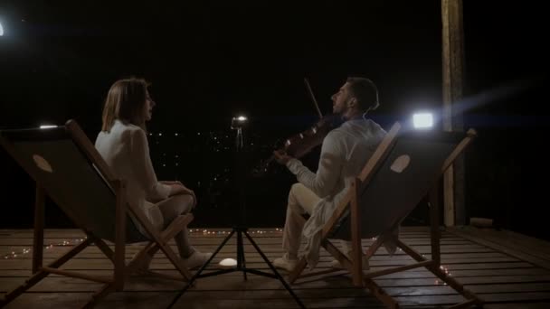 两个音乐家在夜空下演奏 一个男人在街上拉小提琴 一个女孩在晚上的音乐会上唱歌 音乐家们在餐馆的舞台上表演 — 图库视频影像