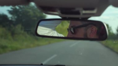 Adam üstü açık bir arabaya biniyor. Güzel kırmızı Cabriolet araba yüksek hızda yolda gidiyor. Seyahat rüyası. Güneşli bir günde güneş gözlüklü bir adam araba sürüyor. Trafikte sürücü güneş gözlüğü takıyor.. 