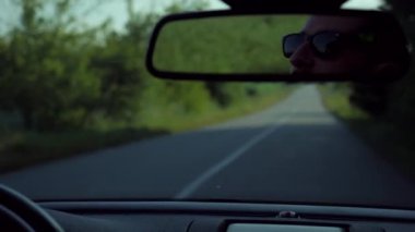 Adam üstü açık bir arabaya biniyor. Güzel kırmızı Cabriolet araba yüksek hızda yolda gidiyor. Seyahat rüyası. Güneşli bir günde güneş gözlüklü bir adam araba sürüyor. Trafikte sürücü güneş gözlüğü takıyor.. 