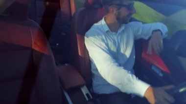 Adam üstü açık bir arabaya biniyor. Güzel kırmızı Cabriolet araba yüksek hızda yolda gidiyor. Seyahat rüyası. Güneşli bir günde güneş gözlüklü bir adam araba sürüyor. Trafikte sürücü güneş gözlüğü takıyor.. 