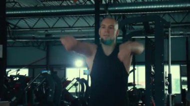 Spor salonunda egzersiz yapan bir adam var. Büyük bir spor salonunda spor yapan bir adam. Bir adam güç egzersizleri yapıyor, boksa hazırlanıyor..