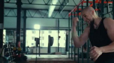 Spor salonunda egzersiz yapan bir adam var. Büyük bir spor salonunda spor yapan bir adam. Bir adam güç egzersizleri yapıyor, boksa hazırlanıyor..