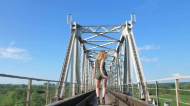 Demiryolu köprüsünde dans eden seksi kadın. Güzel genç dansçı baştan çıkarıcı bir şekilde dans eder ve kalçasını oynatır. Dans eden kız kizomba. Nehir kenarında dans eden seksi, komik kadın. Dışarıda baştan çıkarıcı bir şekilde dans eden güzel bir kadın..