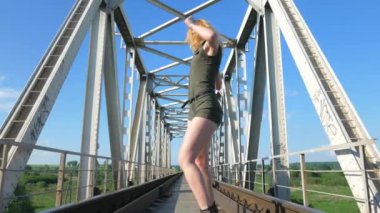 Demiryolu köprüsünde dans eden seksi kadın. Güzel genç dansçı baştan çıkarıcı bir şekilde dans eder ve kalçasını oynatır. Dans eden kız kizomba. Nehir kenarında dans eden seksi, komik kadın. Dışarıda baştan çıkarıcı bir şekilde dans eden güzel bir kadın..