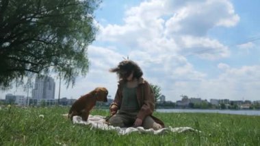 Mutlu kadın ve tüylü arkadaşı parkta güneşli bir günün tadını çıkarıyorlar. Parkta neşeli kahverengi bir köpek olan Cocker Spaniel ile etkileşime giren bir kadın. Gülümseyen kadın, açık havada dost canlısı kahverengi bir köpeği okşuyor. Bir kadın ve kahverengi köpeği arasında sakin bir an.