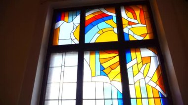 Renkli vitray pencere ve kilisede karmaşık tasarımlar. Süslü cam pencereden süzülen güneş ışığı. Parlak vitraylı camlarda dini figürlerin betimlenmesi. Kilise ortamında titizlikle hazırlanmış vitray sanat eserleri..