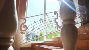 Merdivenlerden yuvarlanan müzik notaları. Merdivenler tuhaf müzik notalarıyla süslenmiş ve güneş ışığıyla aydınlatılmış. Müzik temalı merdiveni olan bir melodiye adım atın. Eğlenceli notalar içeren merdiven tasarımı. Her adımda müzikal titreşimler