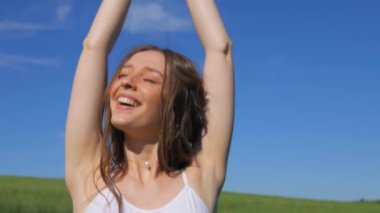 Beyaz elbiseli bir kadın yeşil bir arazide geziniyor. Beyaz elbiseli bir kadın huzurlu bir çayırda zarifçe yürüyor. Huzurlu sahne: Beyaz elbiseli kadın, mavi gökyüzüne karşı tarlada gülümsüyor ve geziniyor. Sakin bir an: zarif giyinmiş kadın 