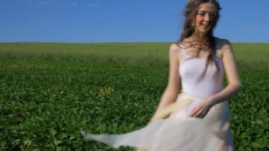 Beyaz elbiseli bir kadın yeşil bir arazide geziniyor. Beyaz elbiseli bir kadın huzurlu bir çayırda zarifçe yürüyor. Huzurlu sahne: Beyaz elbiseli kadın, mavi gökyüzüne karşı tarlada gülümsüyor ve geziniyor. Sakin bir an: zarif giyinmiş kadın 