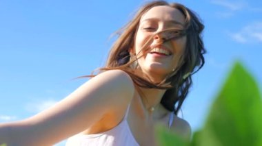 Beyaz elbiseli bir kadın yeşil bir arazide geziniyor. Beyaz elbiseli bir kadın huzurlu bir çayırda zarifçe yürüyor. Huzurlu sahne: Beyaz elbiseli kadın, mavi gökyüzüne karşı tarlada gülümsüyor ve geziniyor. Sakin bir an: zarif giyinmiş kadın 