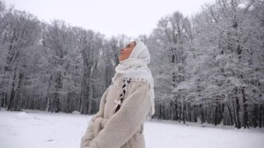Beyaz atkı ve paltolu kadın karlı ormanda duruyor. Karla kaplı ormanda duran bir kadın. Kış sahnesinde beyaz önlüklü bir kadın kış ormanında yürüyor. Karlı orman manzarasında bir kadın. Beyaz önlüklü bir kadınla karlı orman arkaplanı. 