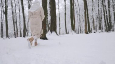 Beyaz atkı ve paltolu kadın karlı ormanda duruyor. Karla kaplı ormanda duran bir kadın. Kış sahnesinde beyaz önlüklü bir kadın kış ormanında yürüyor. Karlı orman manzarasında bir kadın. Beyaz önlüklü bir kadınla karlı orman arkaplanı. 