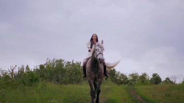 Ormanda ata binen bir kız. Ağaçların ve doğanın ortasında ata binmek. Sahada at sırtında sakin bir kadın. Ormanda binicilik yolculuğu. Kız ve at orman patikalarını keşfediyor. Atlı, nakışlı gömlekli bir kız. Ukrayna