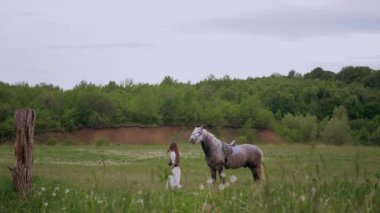 Huzurlu orman ortamında at besleyen bir kadın. Kadının yürüdüğü ve atla ağaçlar arasında bağ kurduğu huzurlu bir an. Sakin orman sahnesinde at ve kadın arasındaki bağ. Tarlada atlara sevgi gösteren bir kadın. At okşayan kadın. 